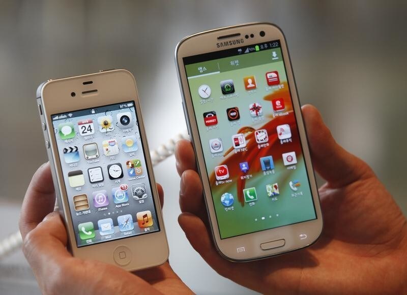 An employee poses as he holds Apple's iPhone 4s (L) and Samsung's Galaxy S III at a store in Seoul August 24, 2012. Samsung Electronics Co's flagship Galaxy smartphone looks very similar to Apple's iPhone, but the South Korean firm has not violated the iPhone design, a Seoul court ruled on Friday. The South Korean ruling comes as the two technology titans are locked in a high-stakes global patent battle that mirrors a fierce rivalry for industry supremacy between two companies that control more than half the world's smartphone sales.