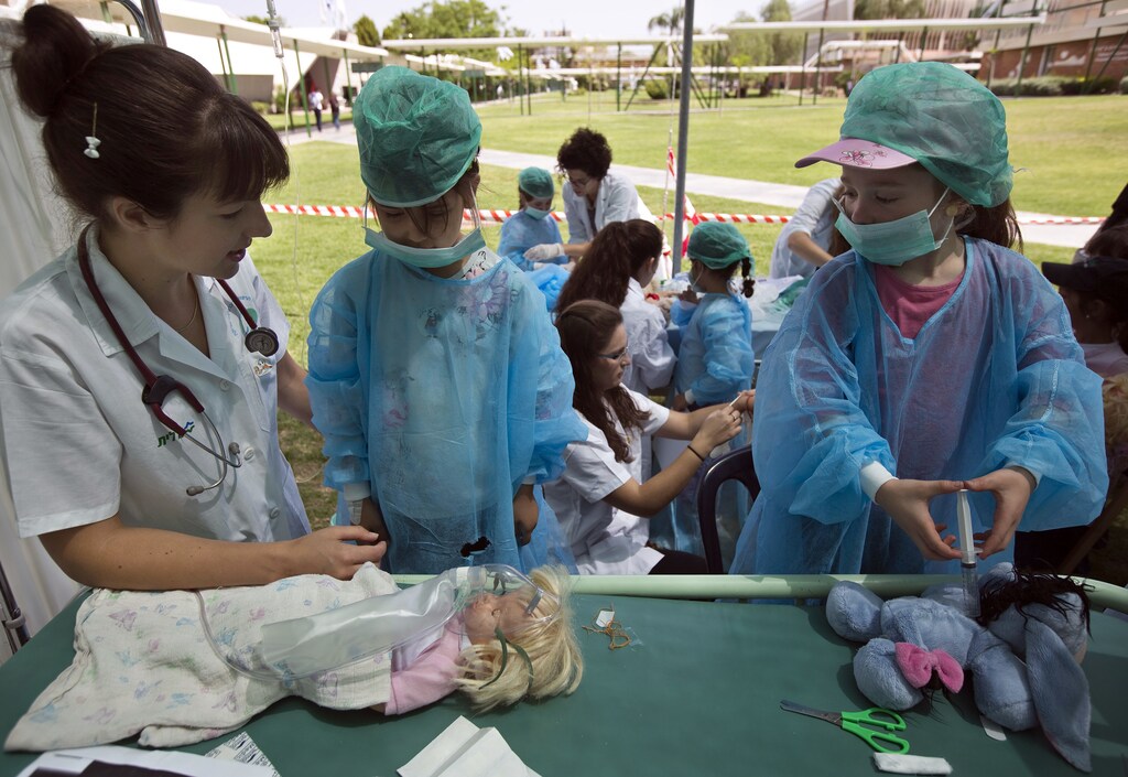 Israeli girls, dressed as surgeons, listen to a student of the faculty of health sciences as part of a project called ‘Teddy Bears Hospital’