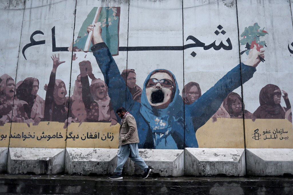 Our collective failure to uphold women’s rights means that we emerge from each crisis a step further away from gender equality. Pictured here: A man walks past a painting on the wall of the former embassy for women's affairs in Kabul, Afghanistan, January 3, 2022.