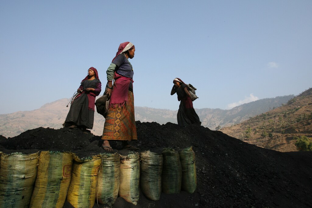 Nepali miners unload sacks of coal near the village of Tila, Rolpa district, the heartland of Maoist insurgents in western Nepal, February 12, 2006. Aid agencies estimate at least 200,000 of Nepal's 26 million people are refugees. At least as many more have left their homes uncounted, many now living with relatives in crowded and impoverished cities or in slums. Millions have also been forced to head south to India in search of work, where they toil as labourers or household servants. Picture taken on February 12, 2006. REUTERS/Desmond Boylan - GM1DRZALJQAA