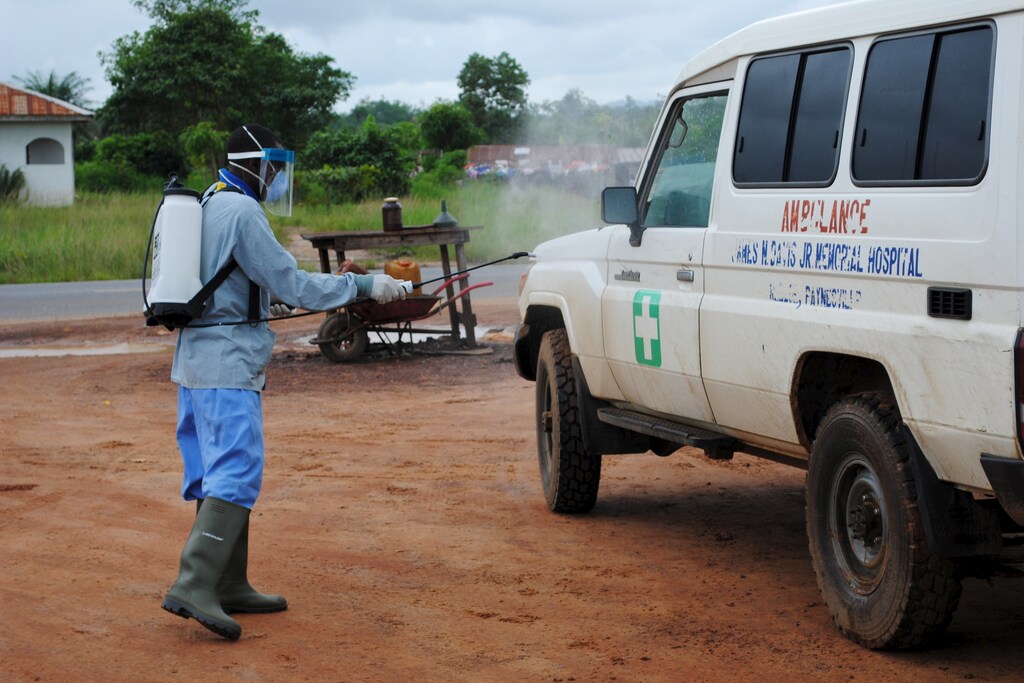 A health worker sprays disinfectant on an ambulance in Nedowein, Liberia, July 15, 2015. A Liberian woman has died of Ebola in a hospital in Monrovia shortly after being admitted, becoming the sixth confirmed case and second death since the virus resurfaced last month, a senior medical official said on Tuesday. REUTERS/James Giahyue - RTX1KE1L
