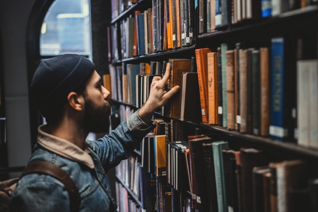 Libraries: A person looking through library books on a shelf