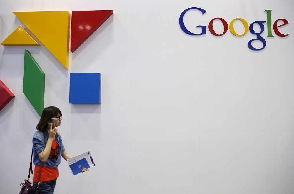 A woman walks past a logo of Google