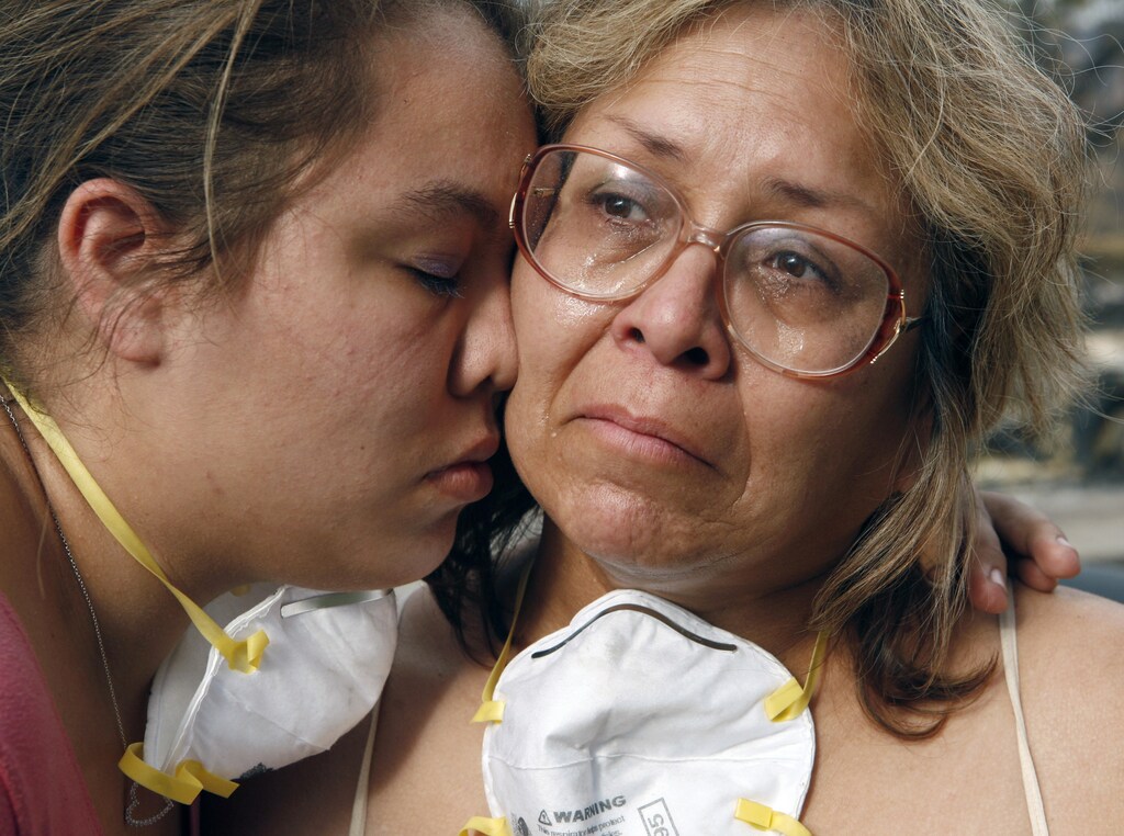 Lori Hutter (R) cries with her daughter Cassie next to their burned out home in the Rancho Bernardo neighborhood of San Diego, California October 27, 2007. Risk Management Solutions, which predicts and assesses insured damages, said in a statement that the wildfires which have devastated Southern California would likely cost insurers between $900 million and $1.6 billion. REUTERS/John Gress (UNITED STATES) - GM1DWLUTSGAA