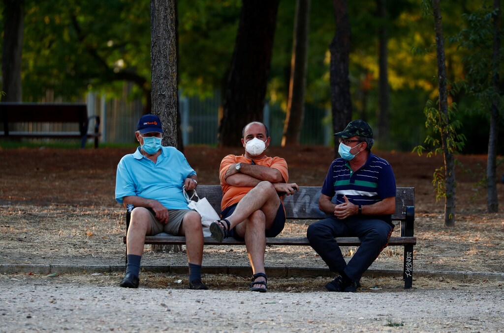 People wearing protective face masks sit at the Las Cruces park amid the coronavirus disease (COVID-19) outbreak in Madrid, Spain July 28, 2020. REUTERS/Javier Barbancho - RC2K2I9HIV0N