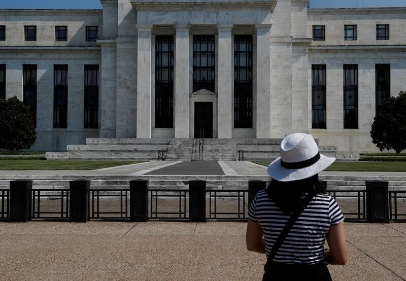 A woman takes a photograph of the Federal Reserve building in Washington, U.S., July 16, 2018.