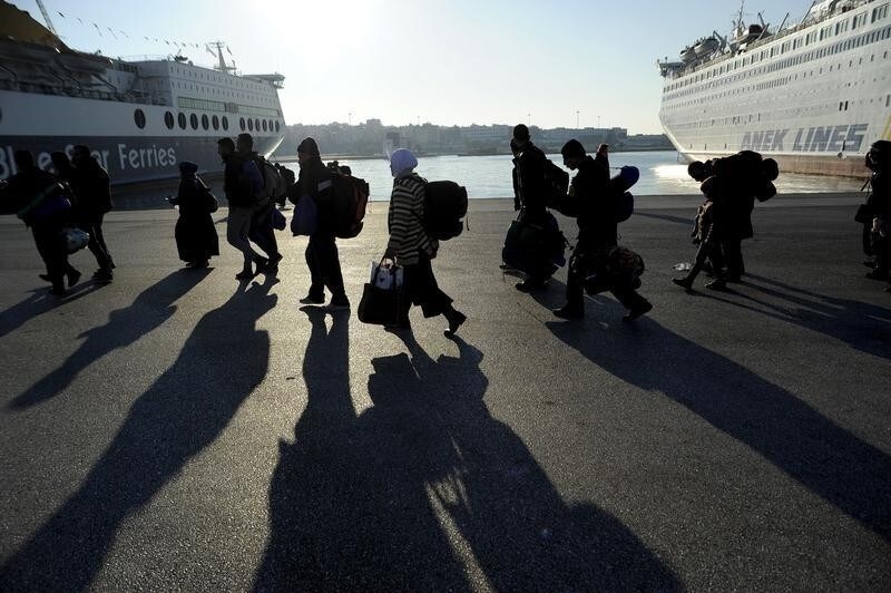 Refugees and migrants walk after disembarking from the passenger ferry Eleftherios Venizelos from the island of Lesbos at the port of Piraeus, near Athens, Greece, December 26, 2015.