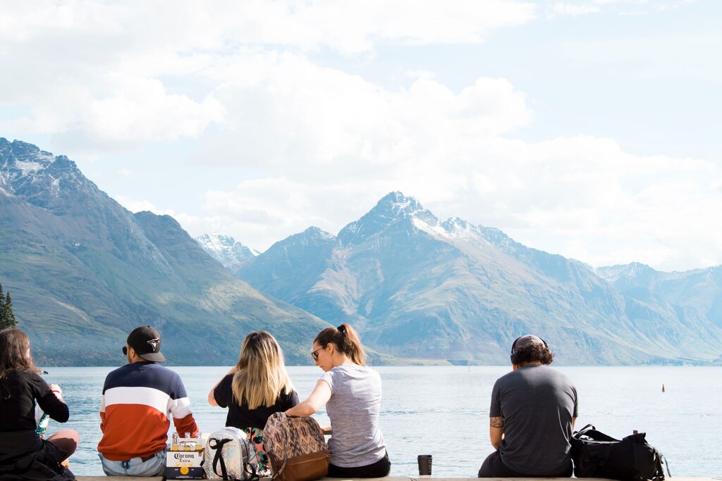 tourists sit on a bench overlooking a lake in a story about sustainable travel