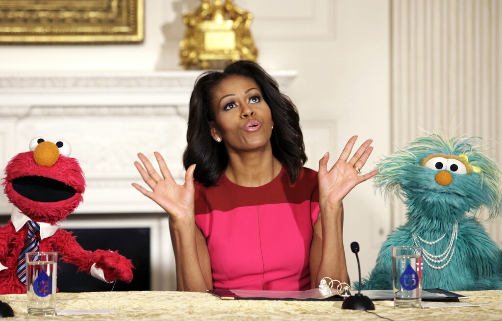 U.S. first lady Michelle Obama reacts between PBS Sesame Street characters Elmo and Rosita after delivering remarks on marketing healthier foods to children at the White House in Washington October 30, 2013. Michelle Obama invited local schoolchildren to participate in the fall harvest of the White House Kitchen Garden. REUTERS/Yuri Gripas (UNITED STATES - Tags: POLITICS SOCIETY ENTERTAINMENT HEALTH FOOD) - GM1E9AV0CXS01