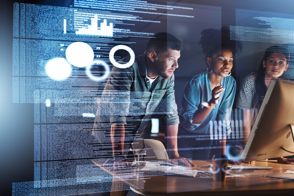 Shot of a group of programmers working together on a computer code at night; human-AI collaboration