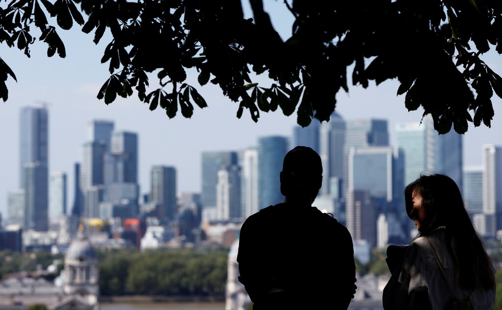 People enjoy the sunny weather in Greenwich Park, with Canary Wharf financial district in the background, in London, Britain, August 7, 2020. REUTERS/John Sibley - RC239I9WL6H9