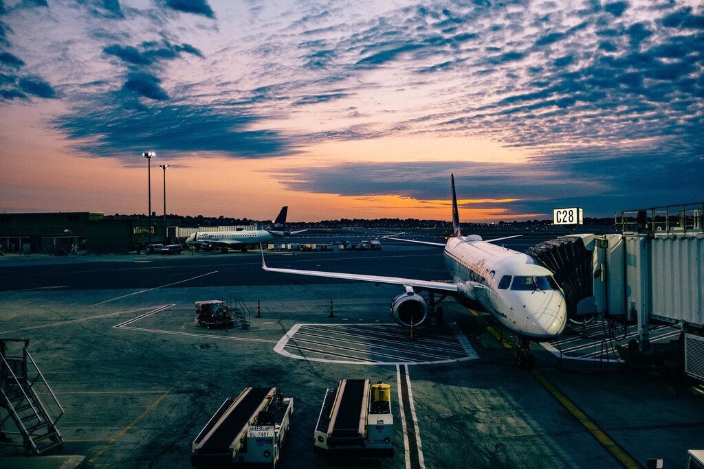 White airplane near trailers during sunset: India can look to sustainable aviation fuel (SAF) to reduce aviation’s carbon footprint.