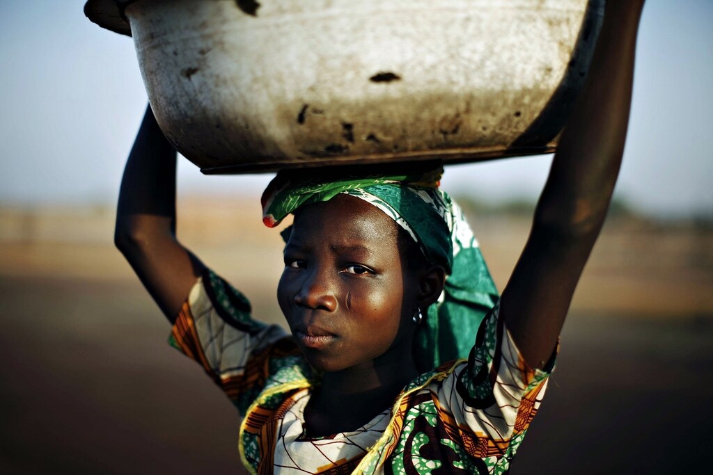 A Ghanian girl waits to sell water as a local boys team practices soccer on a dusty pitch in the northern city of Tamale, January 24, 2008. Ghana is gripped by football fever as it hosts the Africa Cup of Nations soccer tournament over the next three weeks. REUTERS/Finbarr O'Reilly (GHANA) Also see GF2E42T186O01 - RTR1W8L9