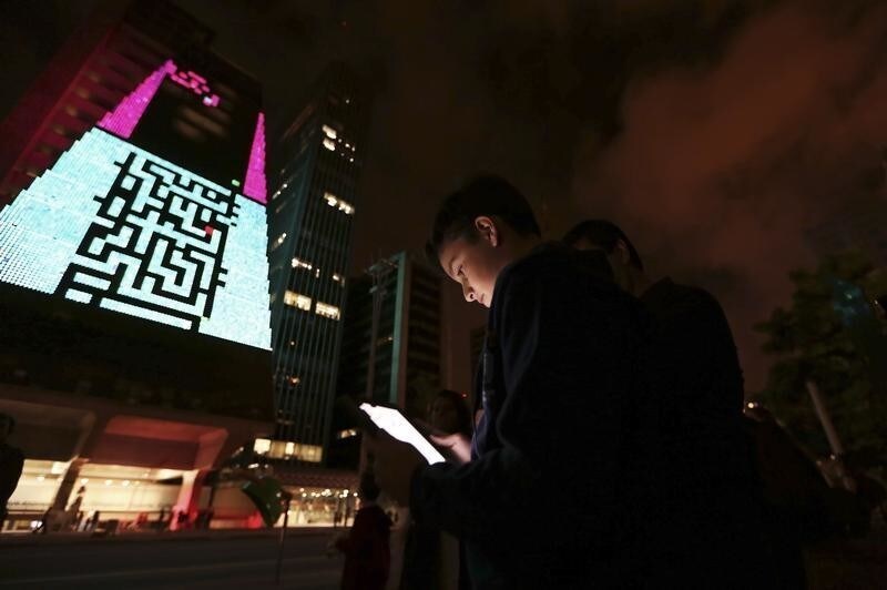 A boy uses an iPad to play a video game, which is projected onto the surface of the Fiesp building, headquarters of the Industry Federation of Sao Paulo, during the "Play!" exhibition in the financial center of Sao Paulo's Avenida Paulista March 27, 2013. The exhibition aims to explore the possibilities of integrating digital art in public space through new communication tools, according to the curator of the event. The games presented in the exhibition are from the 1970s and 80s.
