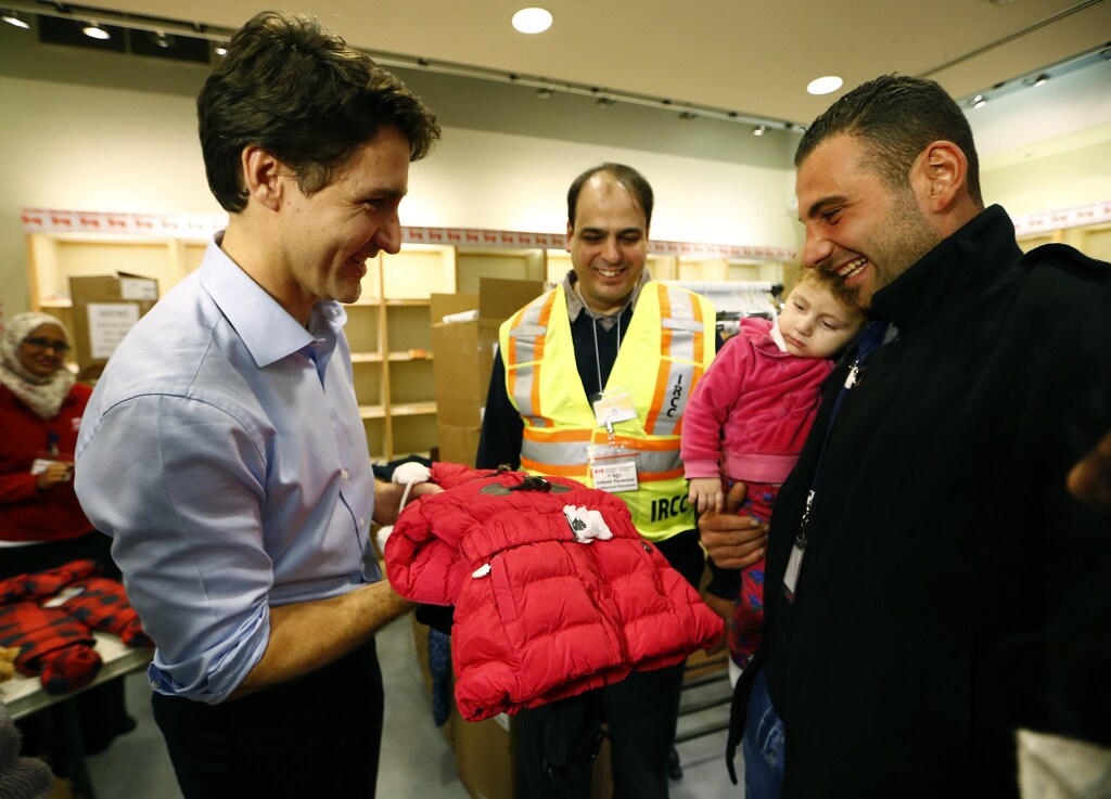 Syrian refugees are presented with a child's winter jacket by Canada's Prime Minister Justin Trudeau on their arrival in Toronto in 2015.