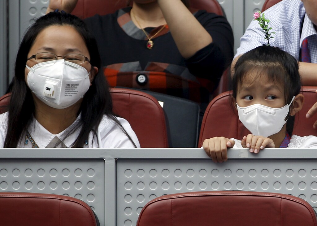 A girl and a woman wearing masks watch the women's singles match between China's Wang Qiang and Caroline Wozniacki of Denmark in a polluted day at the China Open tennis tournament in Beijing, China, October 6, 2015. REUTERS/Kim Kyung-Hoon - GF10000233719