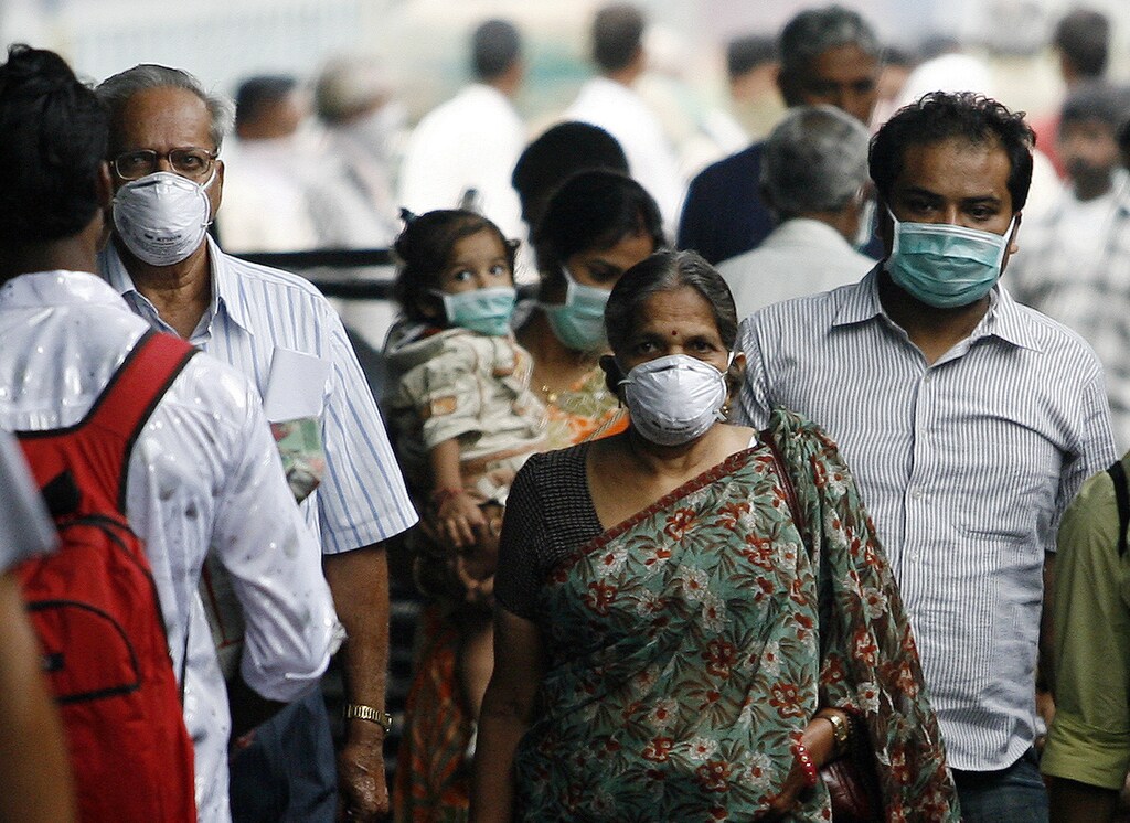 Travellers with masks walk on a railway platform in Pune August 18, 2009. Pune has reported the highest number of deaths caused by H1N1 influenza virus in India, according to a government statement released on Monday. REUTERS/Arko Datta (INDIA SOCIETY HEALTH) - GM1E58I17RJ01