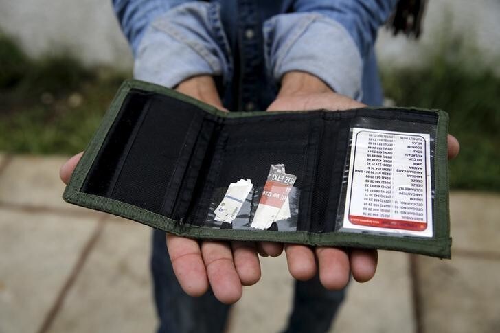 Pakistani migrant Mohamed Ayub, 51, holds the most valuable item he currently owns, his empty wallet, at a deserted hotel used by immigrants for temporary shelter on the Greek island of Kos, Greece May 27, 2015. REUTERS/Yannis Behrakis