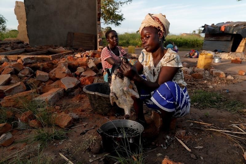 Maria Jofresse, 25, watches her mother Ester Thoma preparing food beside their damaged house in the aftermath of Cyclone Idai, in the village of Cheia, which means "Flood" in Portuguese, near Beira, Mozambique April 4, 2019. Maria Jofresse lost her two children to the storm. In the midst of the floods, she dug their small graves but can't find them anymore. "People suffered indeed but no one suffered as I did because I lost the most precious things I had - my kids," she said. REUTERS/Zohra Bensemra SEARCH "BENSEMRA FLOOD" FOR THIS STORY. SEARCH "WIDER IMAGE" FOR ALL STORIES. - RC1D611B3F40