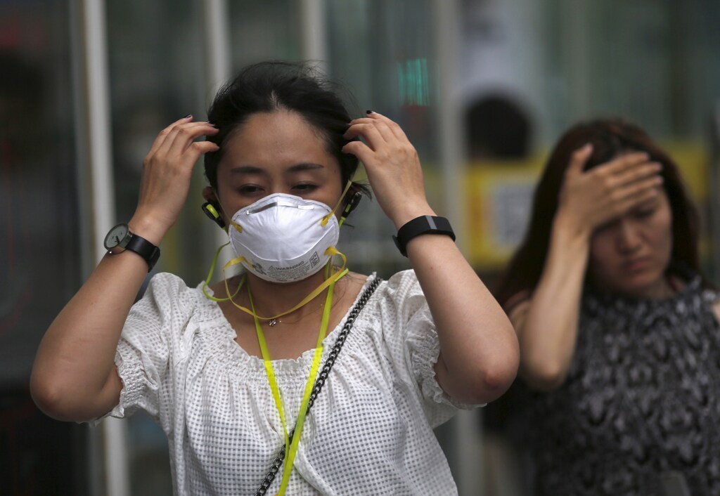 A woman wearing a mask makes her way at a business district during a polluted day in Beijing, China, June 29, 2015.