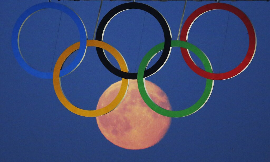 The full moon rises through the Olympic Rings hanging beneath Tower Bridge during the London 2012 Olympic Games August 3, 2012.