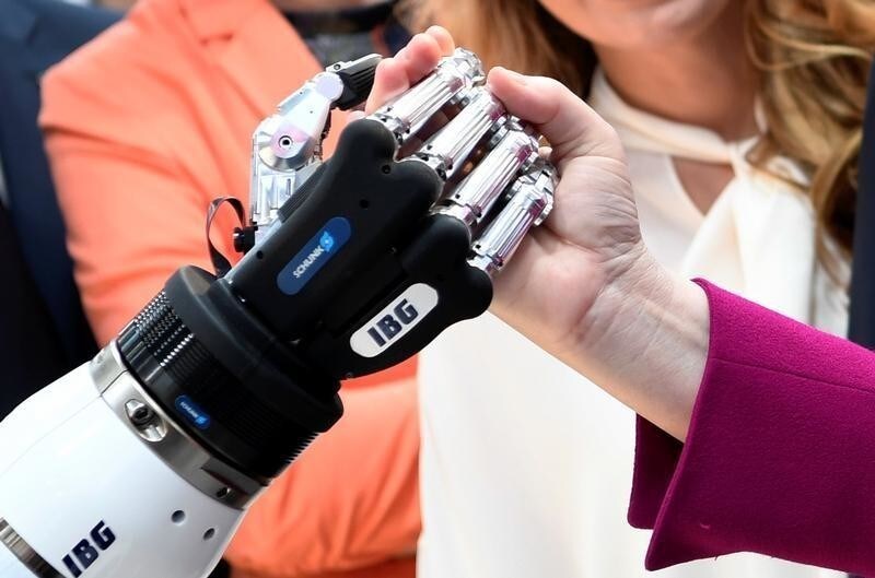 German Chancellor Angela Merkel shakes hands with a humanoid robot at the booth of IBG at Hannover Messe, the trade fair in Hanover, Germany, April 23, 2018.