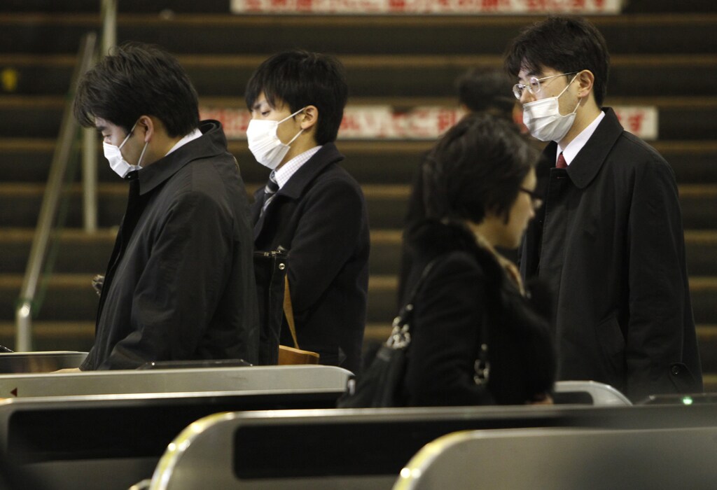 Men wearing masks pass a metro entry gate at a station in Tokyo March 16, 2011. Public trust in the Japanese government faces its biggest test since World War Two over the handling of the nation's nuclear crisis, raising concerns that a breakdown in confidence could fuel panic and chaos if appeals for calm go unheeded. Foreigners are leaving Tokyo, or shutting themselves indoors, and supermarket shelves are running empty despite authorities assuring citizens there is no need to panic from the crisis unfolding at a quake-stricken nuclear power plant. REUTERS/Issei Kato (JAPAN - Tags: BUSINESS DISASTER) - GM1E73G1C2R01