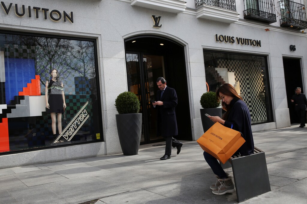 A woman checks her phone after shopping at a Louis Vuitton store in the upscale shopping Serrano Street in central Madrid, Spain January 31, 2017. Picture taken January 31, 2017. REUTERS/Susana Vera - RTX30FN3