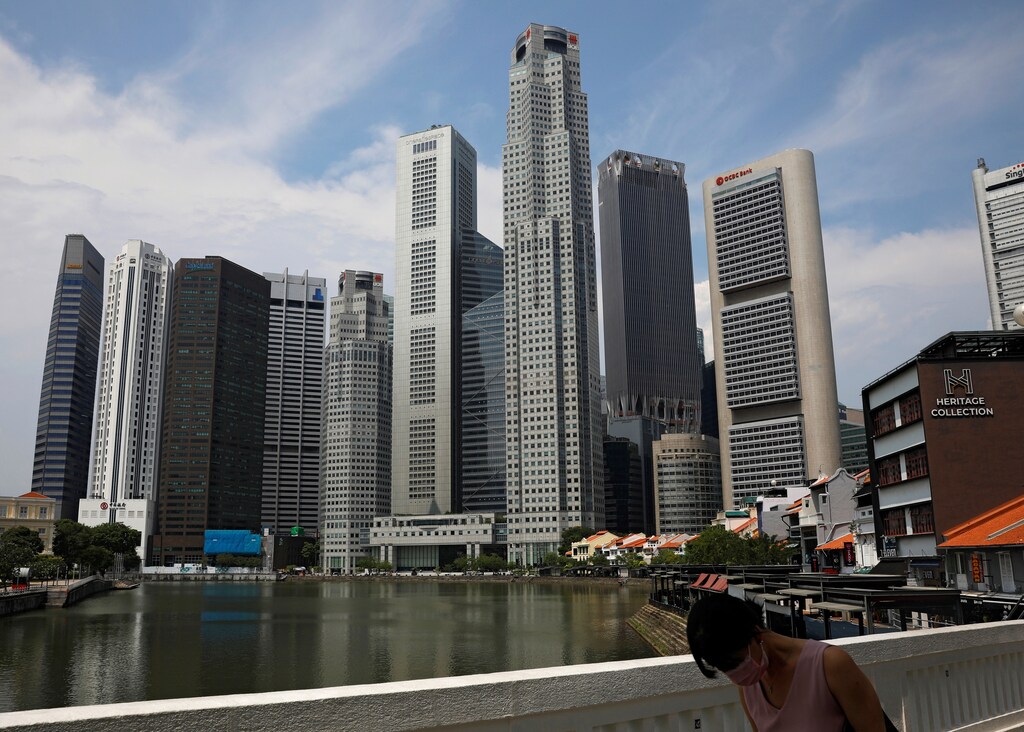 A woman wearing a protective face mask passes the city skyline during the coronavirus outbreak (COVID-19) outbreak in Singapore June 10, 2021. REUTERS/Edgar Su - RC2GXN9K8FOD