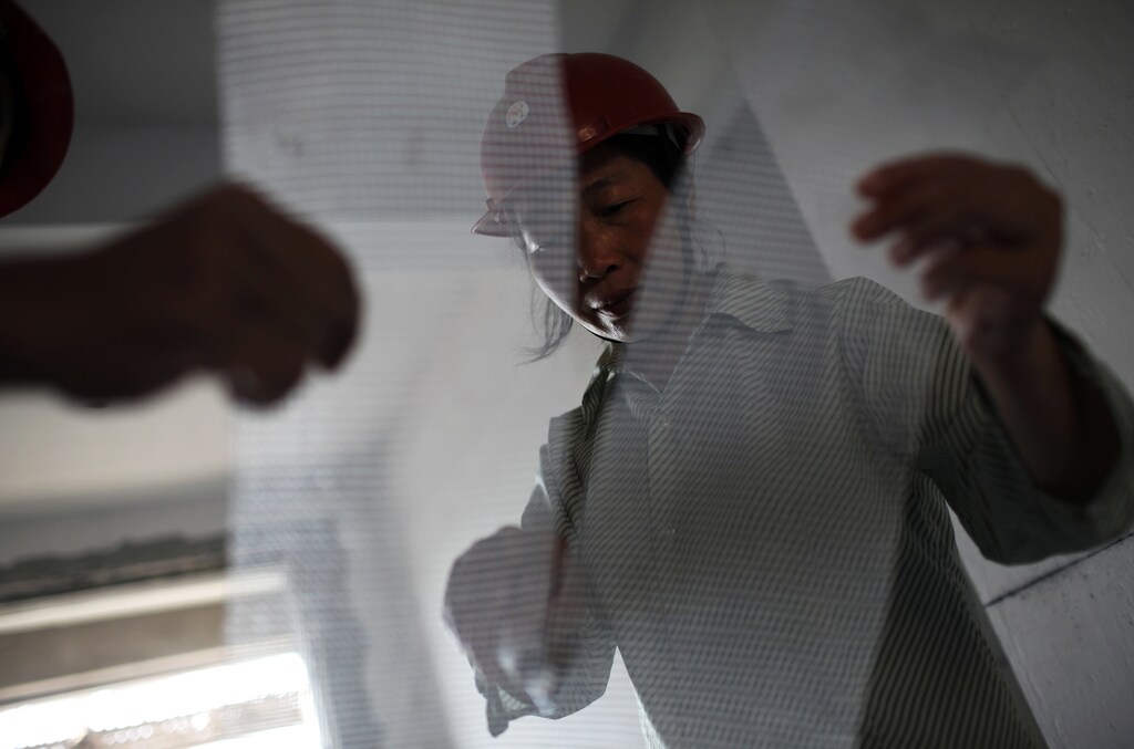Wei Shuqun, a 43-year-old female migrant construction worker, works during a shift at a residential construction site in Shanghai July 17, 2013. The construction site is among a new developing residential area located in Jiading district of suburban Shanghai, some 30 kilometres from the city centre. According to data from the World Bank, 68 percent of China's female population aged 15 and above participate in the labour force, compared to 58 percent in the United States, 51 percent in France, and 53 percent in Germany. Around a third of China's millions of rural-urban migrant workers are women and according to an academic paper published 2010, they also earn around a third less than their male equivalents. Picture taken July 17, 2013. REUTERS/Aly Song (CHINA - Tags: BUSINESS EMPLOYMENT SOCIETY CONSTRUCTION)ATTENTION EDITORS: PICTURE 06 OF 29 FOR PACKAGE 'CHINA'S MIGRANT WORKFORCE'. TO FIND ALL IMAGES SEARCH 'RURAL-URBAN SONG'