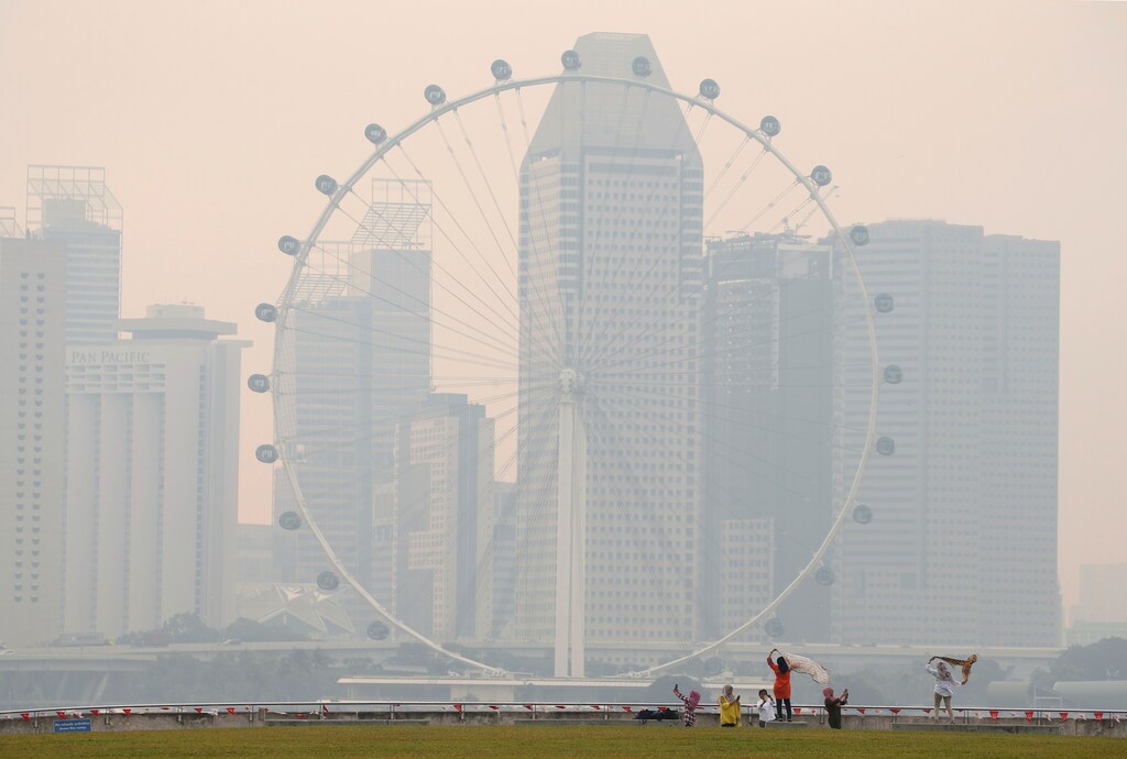 People take photos near the Singapore Flyer observatory wheel shrouded by haze August 26, 2016.