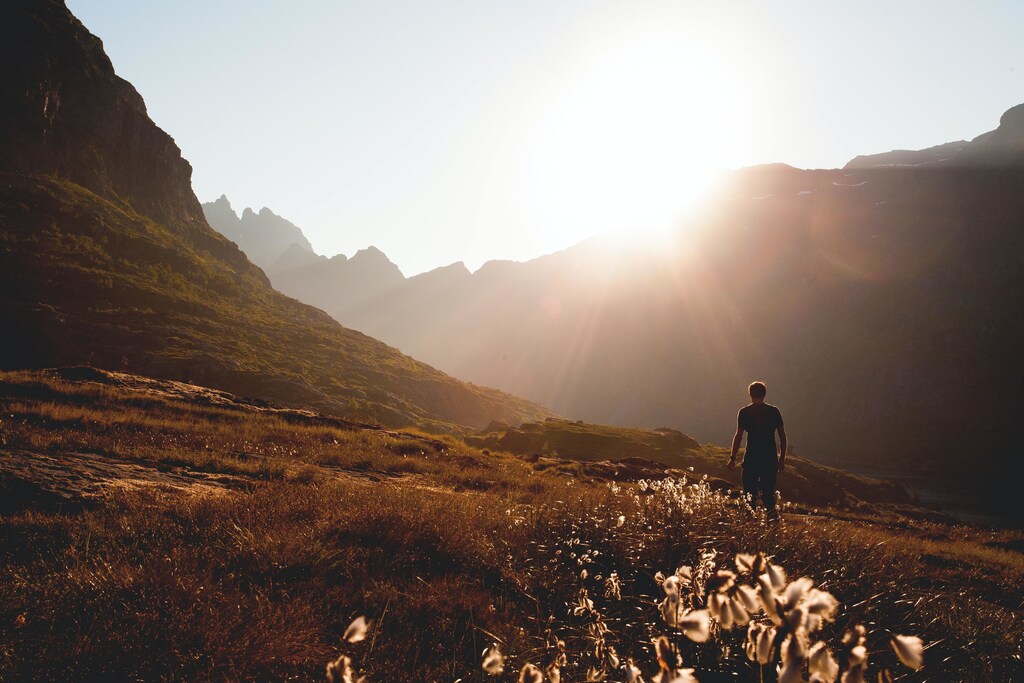 Man walking beside the foot of a mountain.