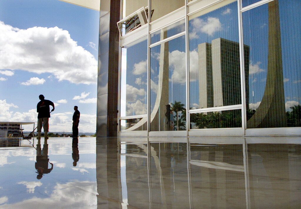 The Congress is reflected in the windows of the Supreme Court building as a worker cleans along its facade in front of 'Tres Poderes' square April 19, 2002. [President Juscelino Kubitschek moved Brazil's capital 700 miles (1,100 kms) inland from Rio de Janeiro 42 years ago this week to open new frontiers in a country larger than the continental United States. He also approved architect and urbanist Lucio Costa's design and layout of this city of two million which today remains one of the cleanest and safest in all Brazil.] Planalto Palace, Brazil's presidency, can be partially seen at far left. - RTXL80T