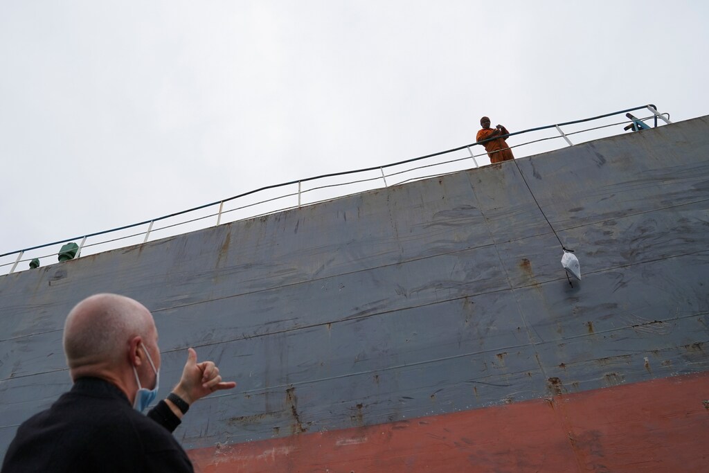 Reverend Stephen Miller of the Mission to Seafarers gestures at a sailor pulling up a bag on a bulk carrier, during a trip to deliver supplies to those stranded on visiting cargo vessels due to the coronavirus disease (COVID-19) pandemic, in Hong Kong, China March 22, 2021. Picture taken March 22, 2021. REUTERS/Lam Yik - RC2PKM91E4B6