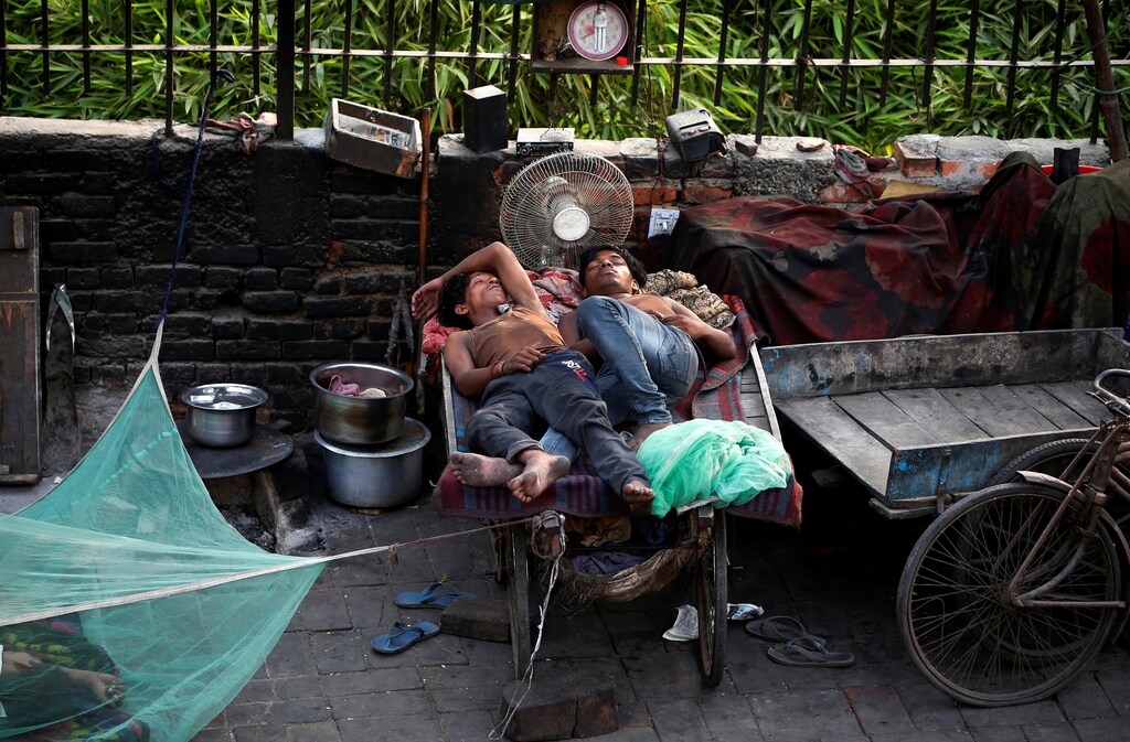 People sleep on a hand cart at a roadside on a hot day in New Delhi, India, June 1, 2018. REUTERS/Amit Dave - RC1BADEA75D0