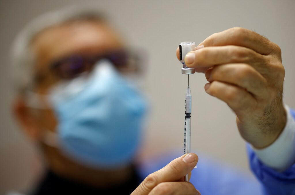 A man fills a vaccine syringe