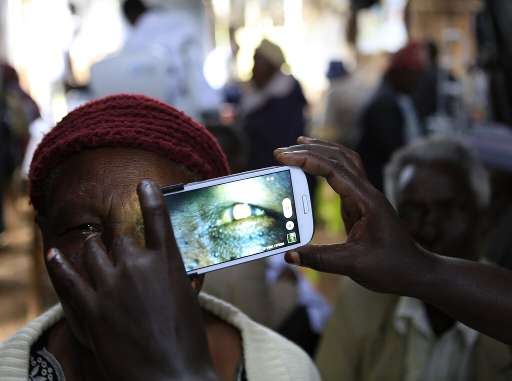 A woman undergoes an eye examination using a smartphone at a temporary clinic by International Centre for Eye Health at Olenguruone in the Mau Summit 350km (217 miles) west of Kenya's capital Nairobi, October 29, 2013. The organisation is running clinics for 5000 eye patients using a new application "Peek Vision" that enables doctors to give patients a full eye examination using smartphones. The phone diagnoses and conducts cataract scans, basic eye tests, and uses the phone's flash to illuminate the back of the eye for signs of disease. It also sends all recorded data of a patient along with their location to a doctor for analysis. REUTERS/Noor Khamis (KENYA - Tags: HEALTH SOCIETY SCIENCE TECHNOLOGY) - RTX14SX7