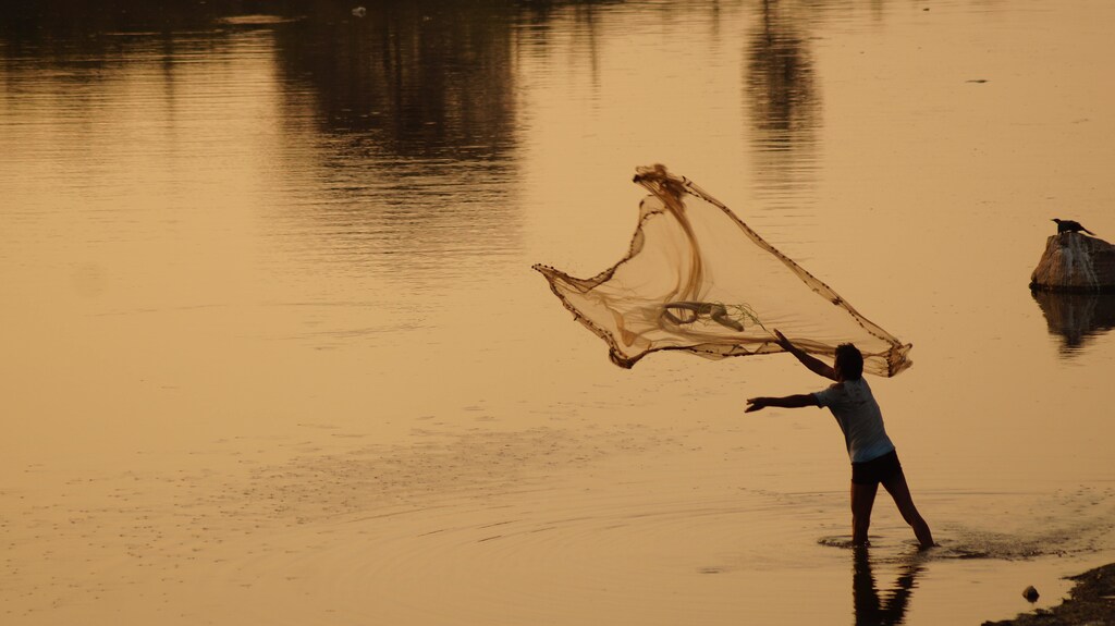 A man throwing a fishing net into the water.