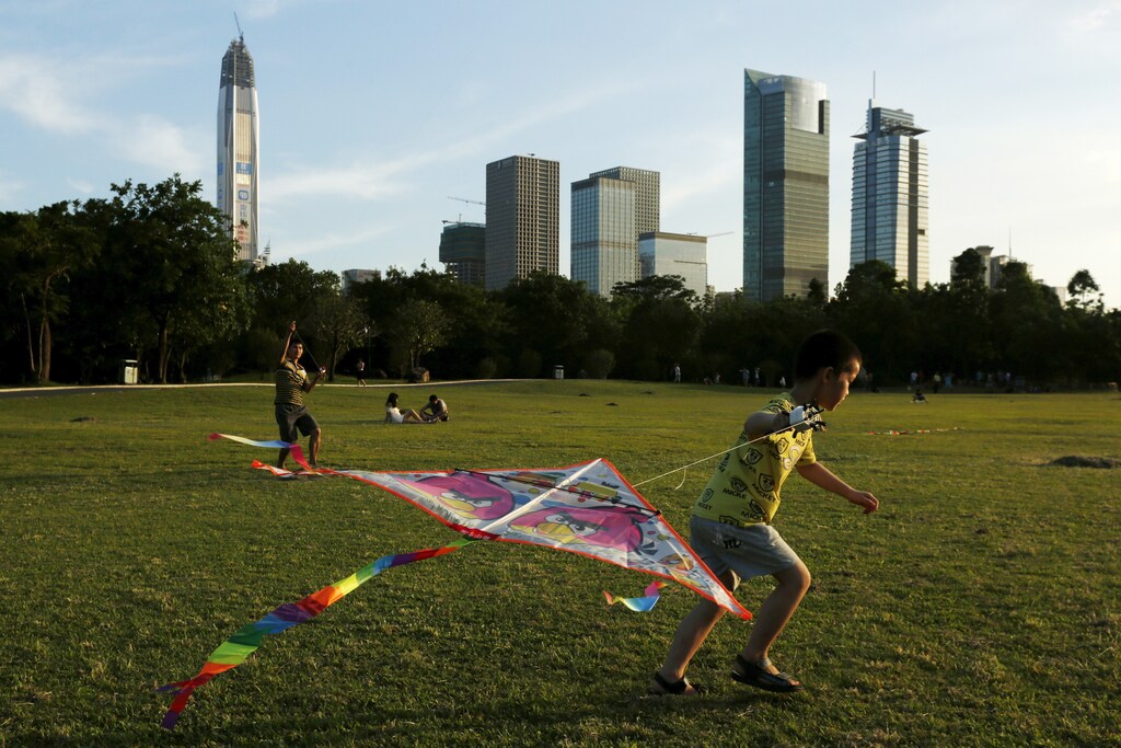 People fly kites at a park in front of commercial towers, including the 115-storey Ping An International Finance Centre (L), which is under construction, in Shenzhen, China August 3, 2015. A stream of weak manufacturing data, the fall in the yuan and a stock market rout have painted a gloomy picture of the world's second largest economy over the past few months. But for the property market in China's boomtown of Shenzhen, thing's couldn't be better. Real estate prices in China's answer to Silicon Valley rose by almost a third in August from the same month a year-ago, a further climb from the nearly 24 percent year-on-year increase in July, official data showed, making it the country's hottest property market by far. Picture taken August 3, 2015. REUTERS/Bobby Yip - RTS35PR