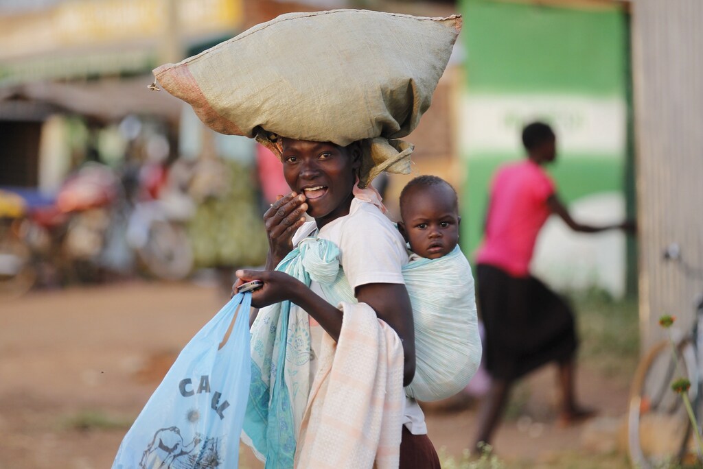 A woman carries a child and a bag on her head within the trading centre of the U.S. President Barack Obama's ancestral village of Nyang'oma Kogelo, west of Kenya's capital Nairobi, July 15, 2015. President Obama visits Kenya and Ethiopia in July, his third major trip to Sub-Saharan Africa after travelling to Ghana in 2009 and to Tanzania, Senegal and South Africa in 2011. He has also visited Egypt, in North Africa, and South Africa for Nelson Mandela's funeral. Obama will be welcomed by a continent that had expected closer attention from a man they claim as their son, a sentiment felt acutely in the Kenyan village where the 44th U.S. president's father is buried. Picture taken July 15, 2015. REUTERS/Thomas Mukoya - GF10000168089