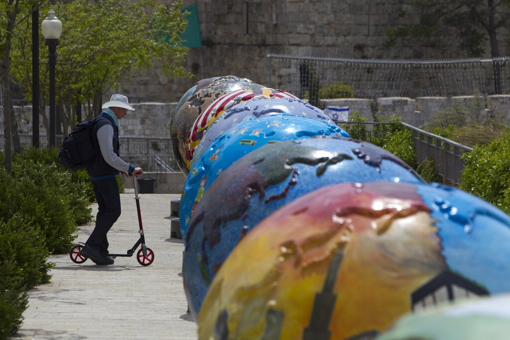 A man rides a scooter near giant globes displayed outside the walls of Jerusalem's Old City April 17, 2013.