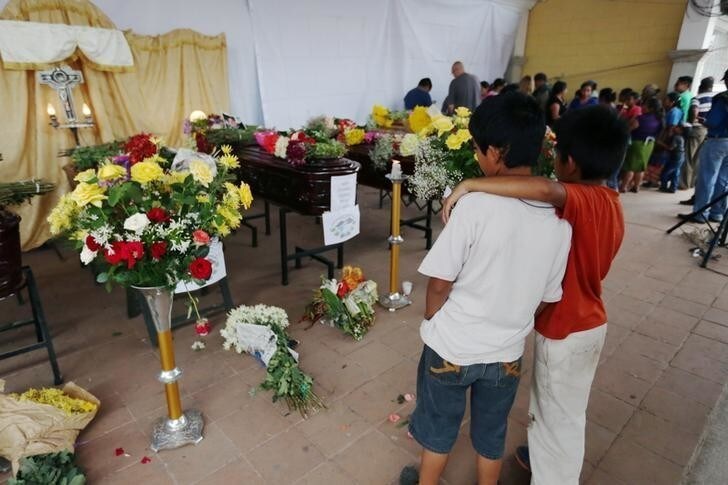 Children watch coffins of victims who died during the eruption of the Fuego volcano, during a wake at a plaza in Alotenango, Guatemala June 4, 2018. REUTERS/Jose Cabezas