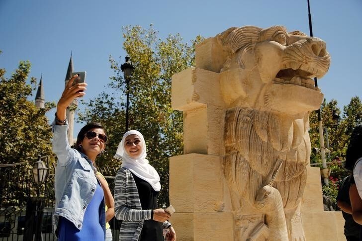 Syrian women take selfies in front of the restored Lion of al-Lat, a 2,000-year old statue, on display in Damascus, Syria October 1, 2017. REUTERS/Omar Sanadiki