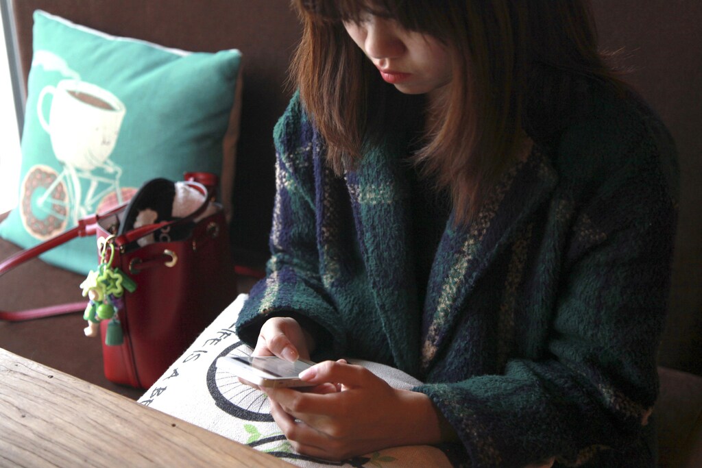 A woman uses an app on a mobile phone at a cafe in Beijing, China, April 11, 2016. REUTERS/Shirley Feng/File Photo - RTSF49A