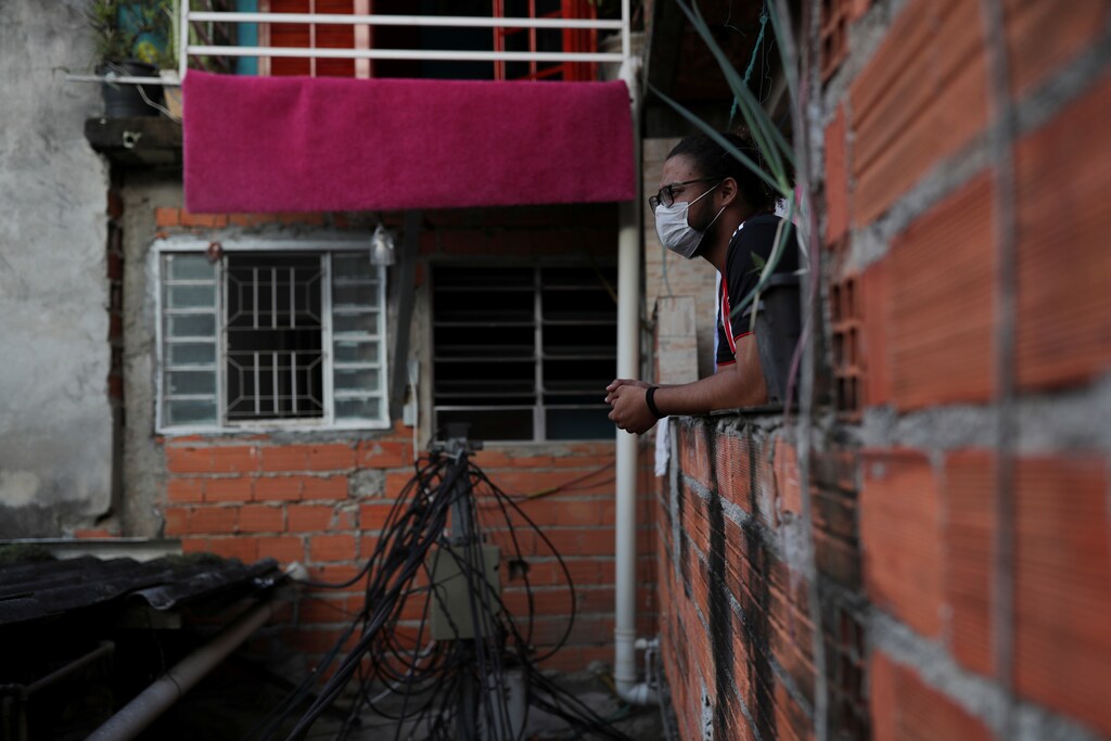 Marcus Vinicius Conceicao dos Santos, 22, looks out from his home as he self-isolates with another 19 people after showing symptoms of coronavirus disease (COVID-19), in the city's biggest slum Paraisopolis after residents have hired a round-the-clock private medical service, in Sao Paulo, Brazil March 30, 2020. Picture taken March 30, 2020. REUTERS/Amanda Perobelli - RC2GWF9GGCOC