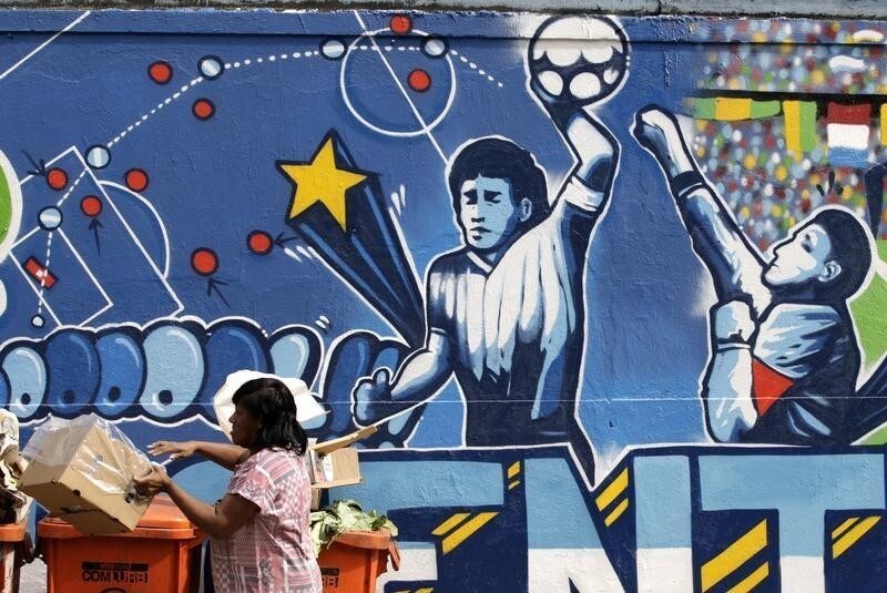 A resident stands near a mural depicting the famous "Hand of God" goal by former Argentine soccer star Diego Maradona, in light of the upcoming 2010 FIFA World Cup at the Agua Santa neighborhood in Rio de Janeiro May 21, 2010. REUTERS/Sergio Moraes (BRAZIL - Tags: SPORT SOCCER WORLD CUP SOCIETY) - GM1E65M05VS01