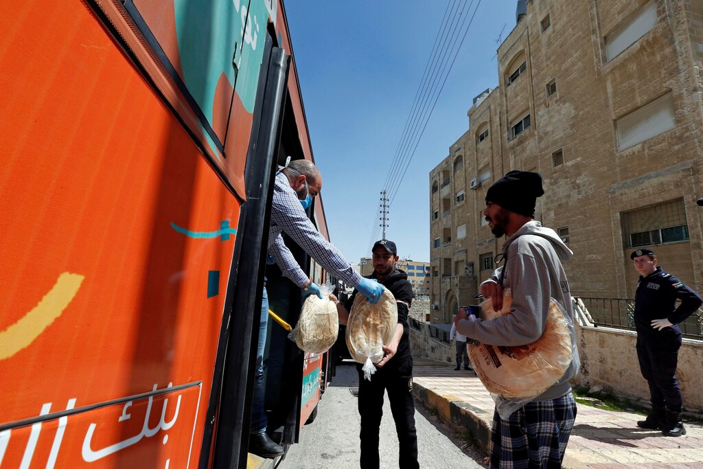 People buy bread from a bus delivering food after Jordan announced it would extend a curfew indefinitely, amid concerns over the spread of coronavirus disease (COVID-19), in Amman, Jordan March 24, 2020. REUTERS/Muhammad Hamed