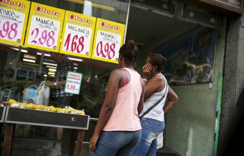 Women look at prices at a food market in Rio de Janeiro, Brazil, January 21, 2016. Brazil's real currency slipped to near its weakest ever against the U.S. dollar on Thursday as investors worried that erratic policy signals from President Dilma Rousseff may prolong a crippling recession in Latin America' biggest economy. REUTERS/Pilar Olivares - GF20000102653