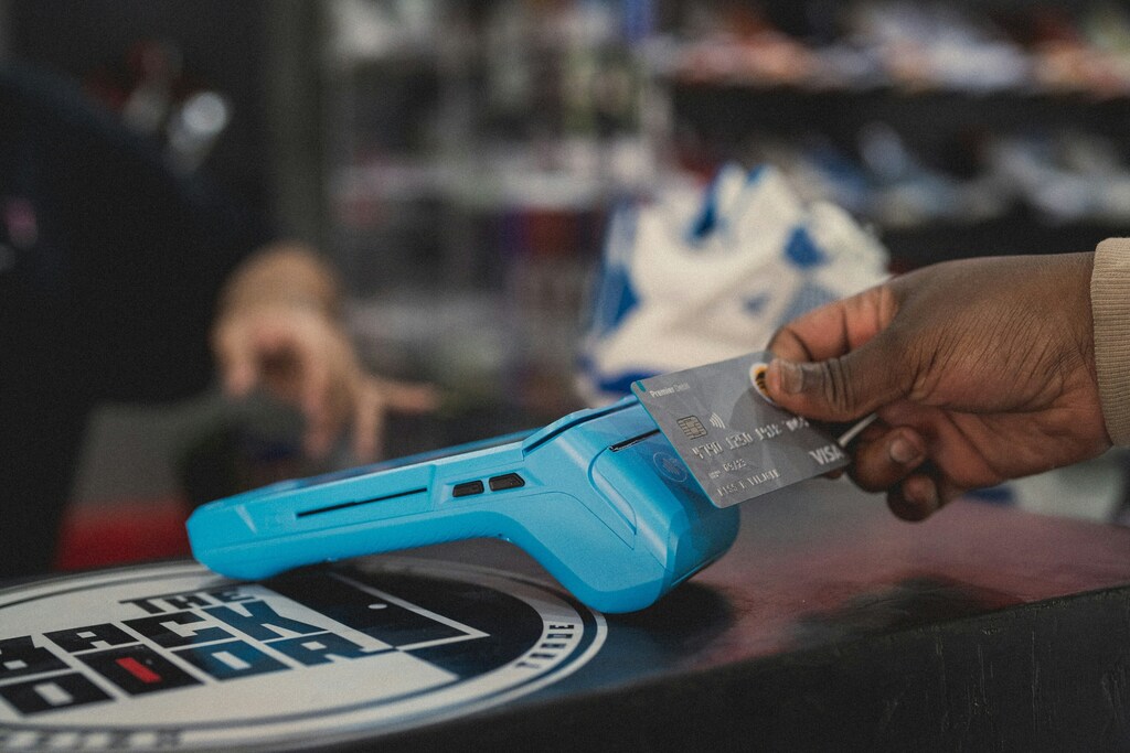 Someone is seen tapping their debit card on a payment machine.