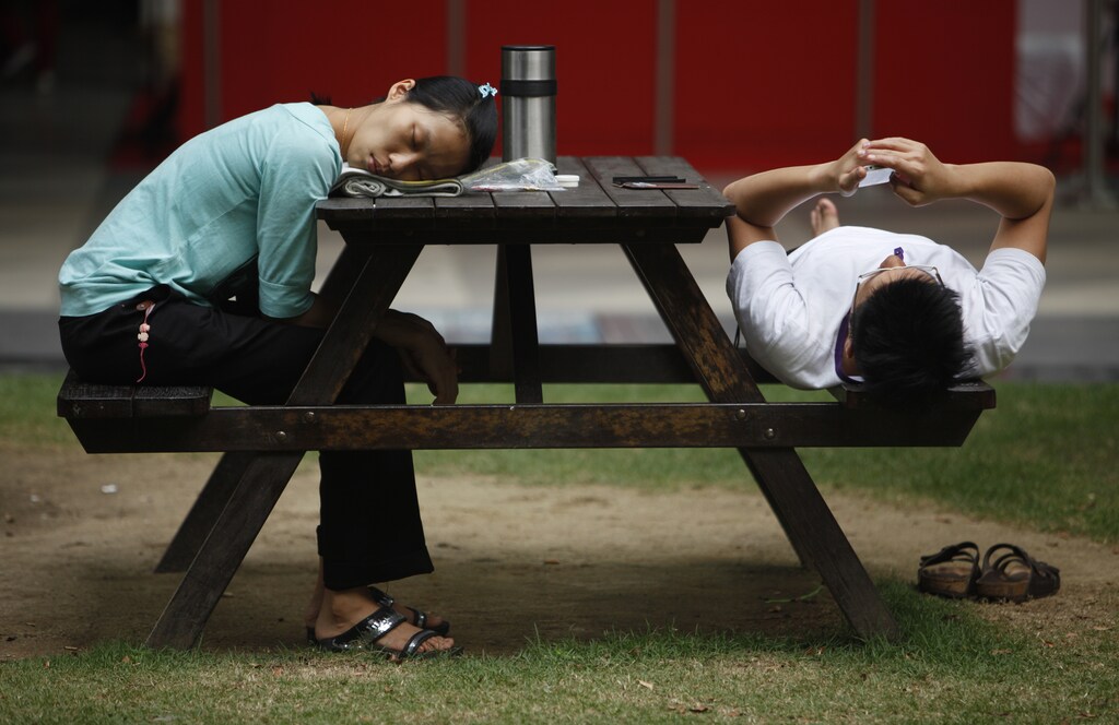 A woman sleeps at a bench at the end of a working day at the central business district of Singapore November 28, 2013. REUTERS/Edgar Su (SINGAPORE - Tags: SOCIETY) - GM1E9BS1NZ801